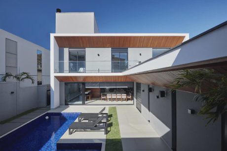 Modern two-story house with wood accents, glass balcony, pool, and patio.