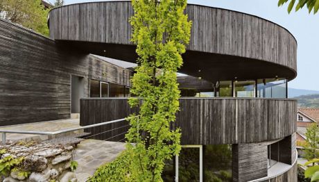 Curved wooden building facade with vine and balcony railings.