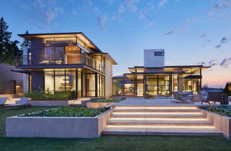 Modern house with large windows at dusk, featuring outdoor stairs and lighting.