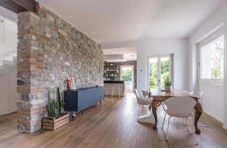 Modern dining room with stone accent wall, hardwood floors, and minimalist decor.