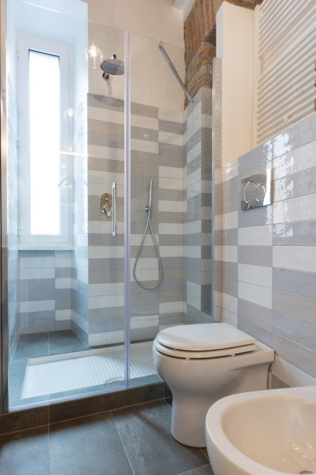 Contemporary bathroom with striped tile shower and exposed brick.