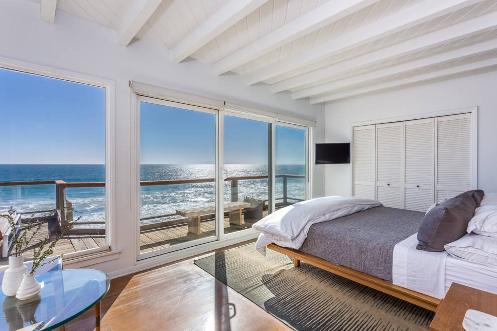 Modern bedroom with large windows overlooking the ocean.