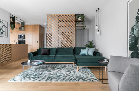 Contemporary living room with emerald couch and wooden accents.