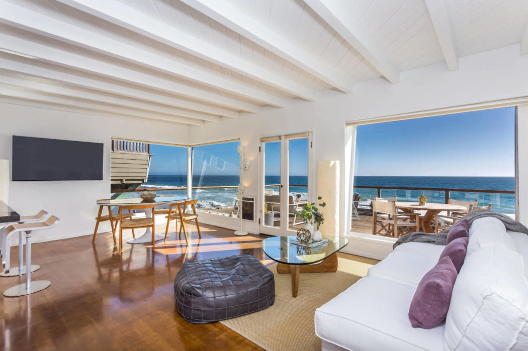 Bright beachfront living room with white decor and ocean view.