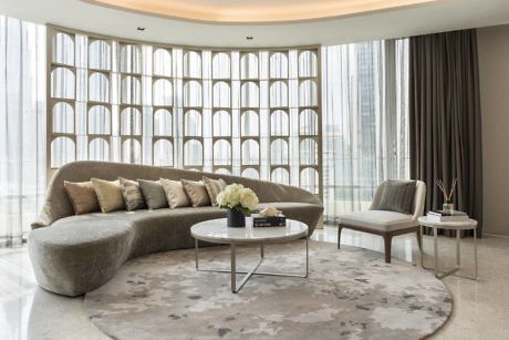 Modern living room with curved sofa and floor-to-ceiling windows.