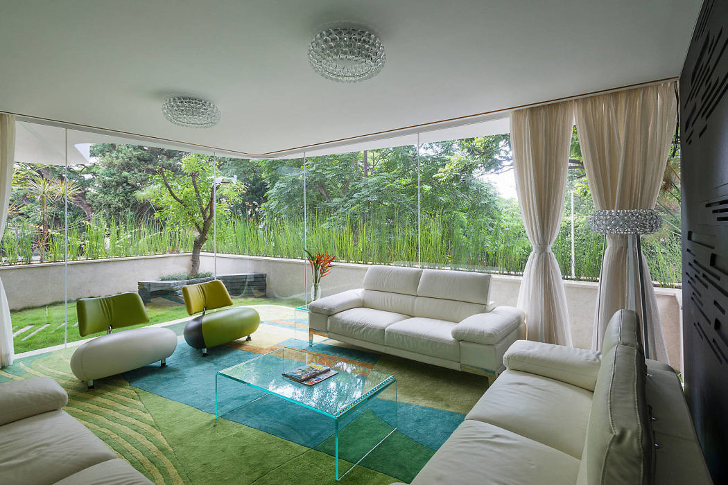 Modern living room with large windows overlooking greenery.