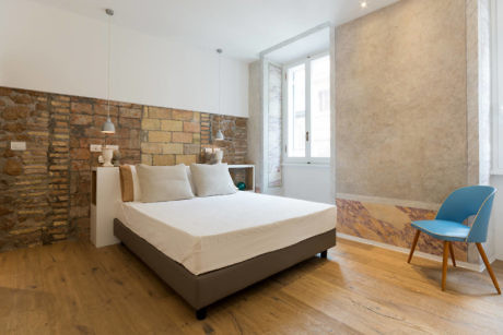 Modern bedroom with exposed stone walls and hardwood floors.