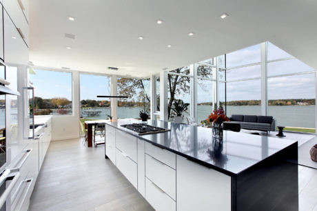 Modern kitchen with sleek white cabinets and a lake view.