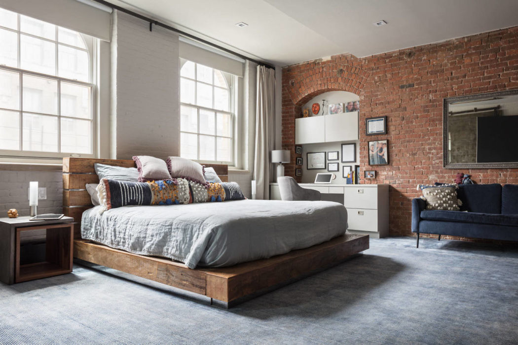 Industrial-chic bedroom with exposed brick and large windows.
