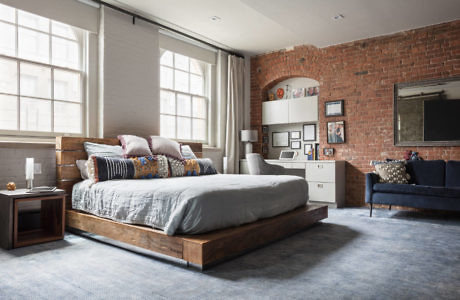 Industrial-chic bedroom with exposed brick and large windows.