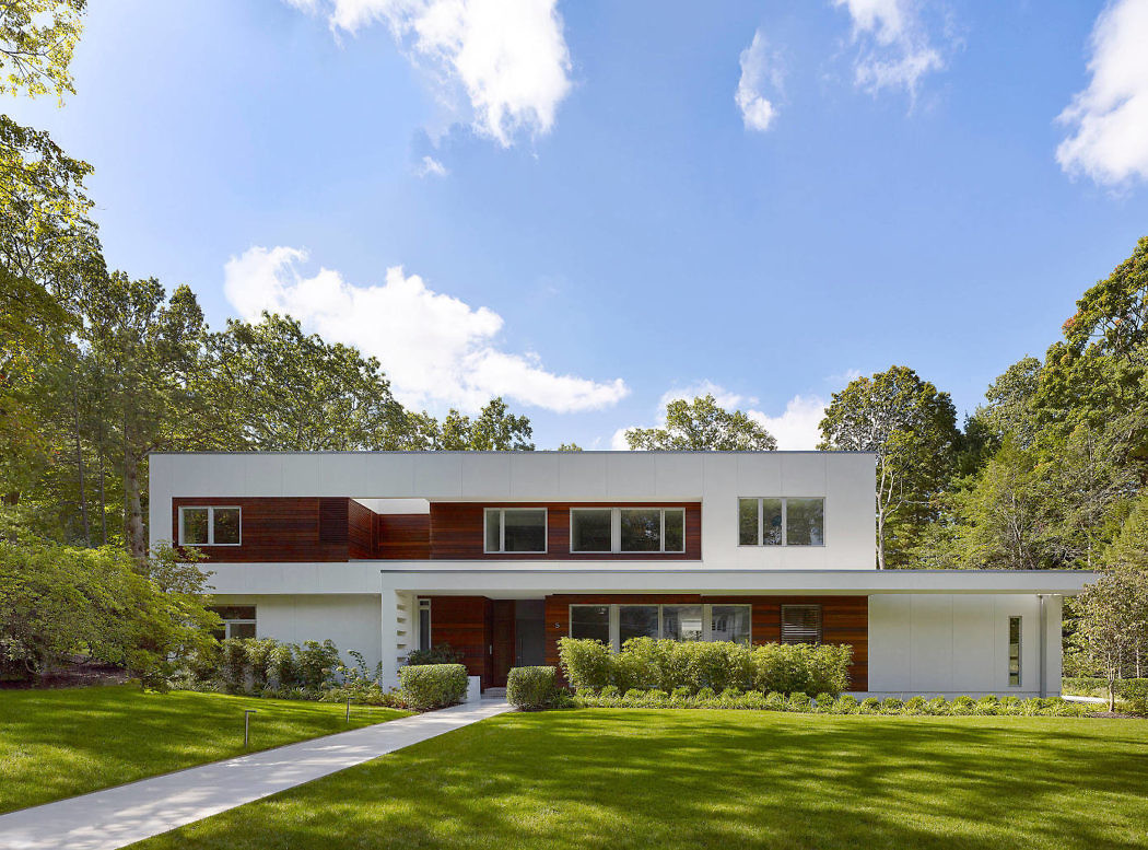 Contemporary two-story home with contrasting wood and white facade, surrounded by lush green