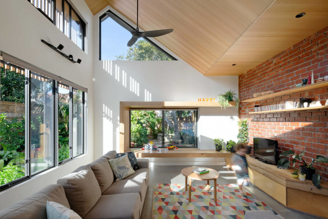 Modern living room with brick wall, large windows, and geometric-patterned floor.