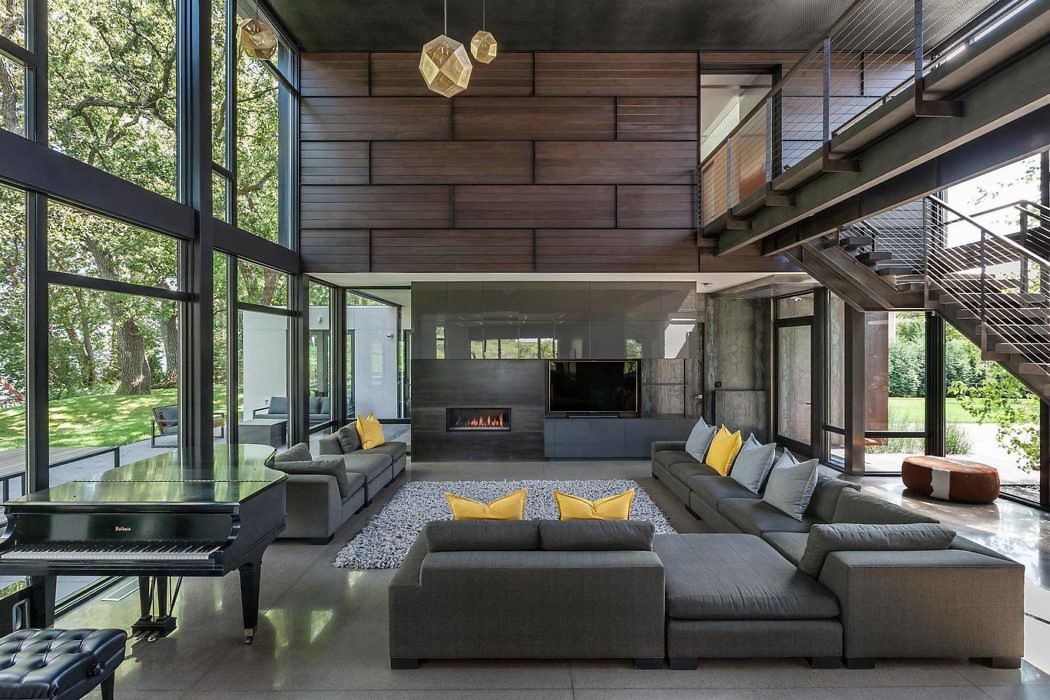 Contemporary living room with large windows, sectional sofa, and suspended lighting.