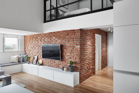 Exposed brick wall in a contemporary living room with a loft bed above.