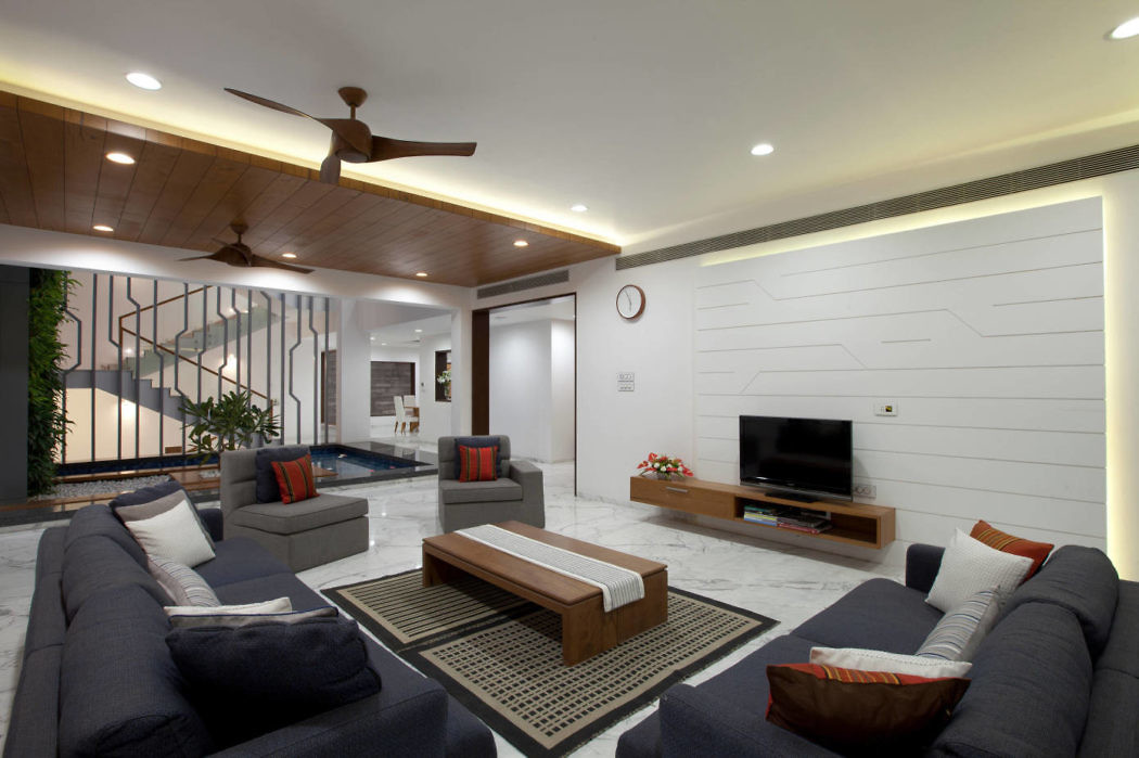 Modern living room with blue sofas, wooden ceiling, and white walls.