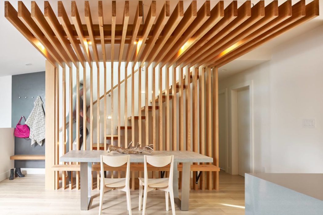 Modern dining room with wooden slat partition and minimalist furniture.