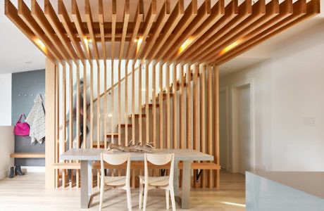 Modern dining room with wooden slat partition and minimalist furniture.