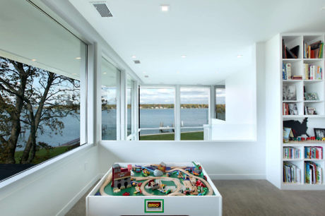 Modern room with large windows, lake view, and a toy train set.