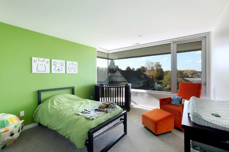 Bright bedroom with a green wall, modern furniture, and large windows.
