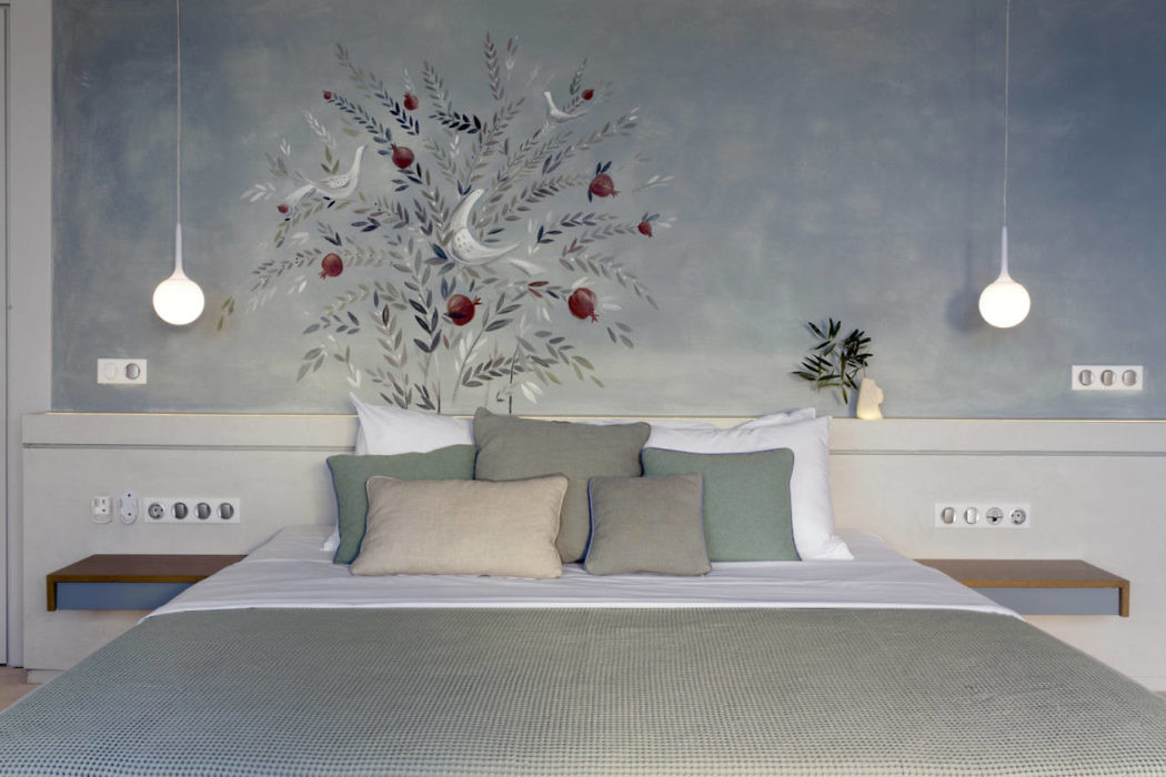Modern bedroom interior with painted tree mural and pendant lights.