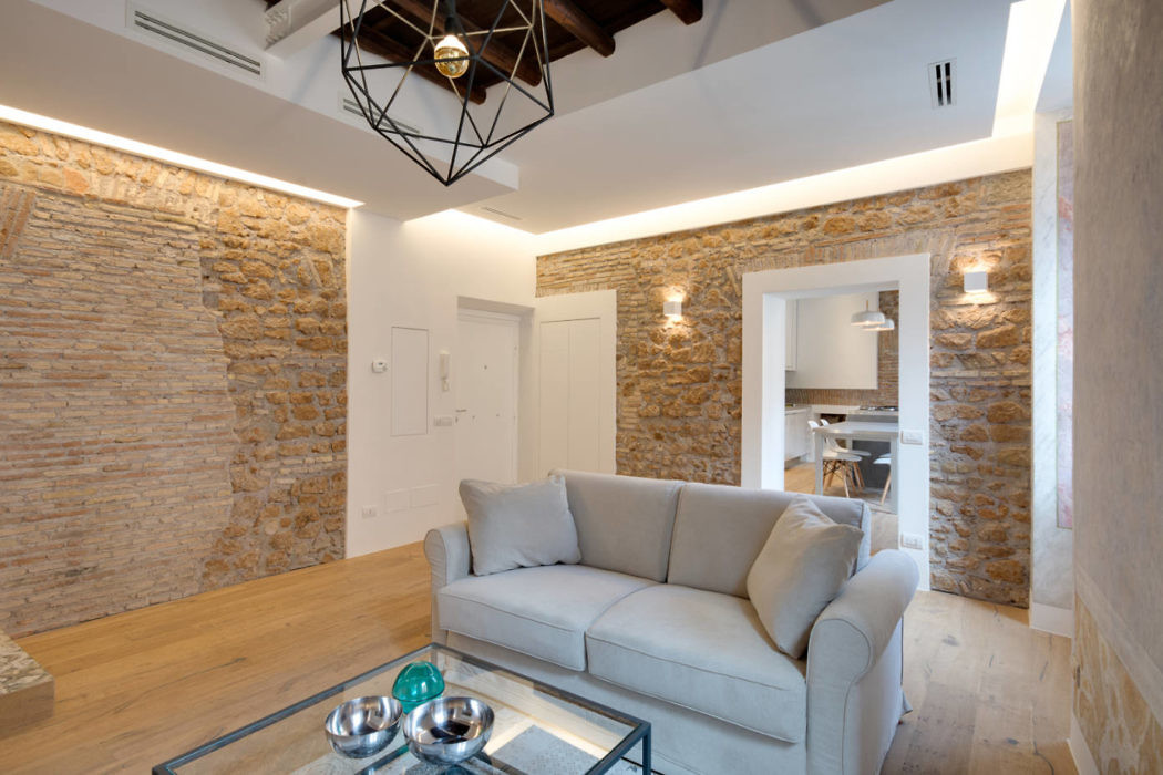 Modern living room with exposed stone walls and a geometric ceiling light.