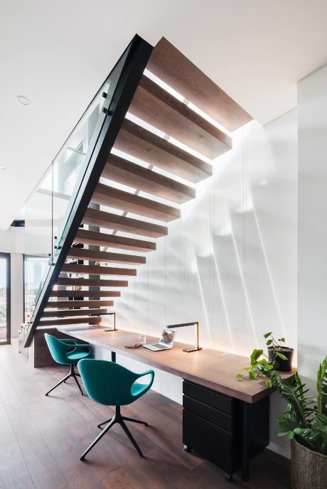 Contemporary floating wooden staircase with integrated workspace beneath.