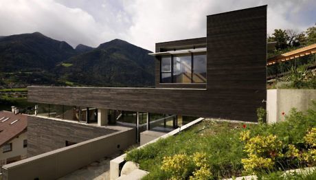 Modern house with horizontal lines blending with mountainous background.