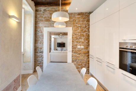 Modern kitchen with white cabinets and exposed stone walls.