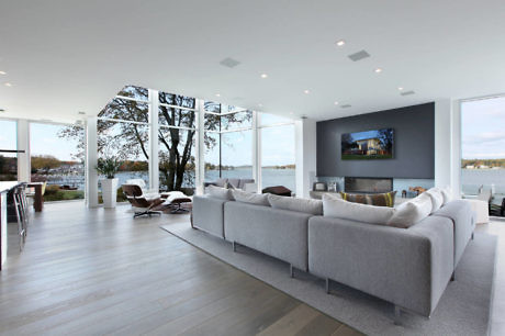 Modern living room with large windows overlooking a body of water.