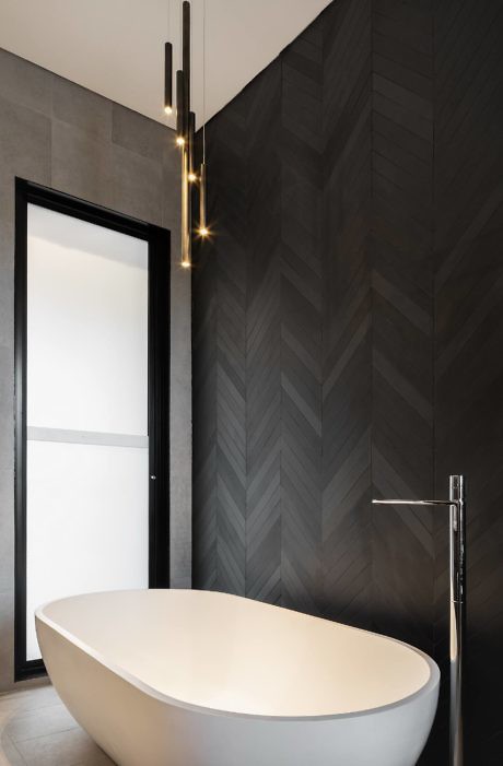 Modern bathroom with a freestanding tub and herringbone-patterned wall tiles