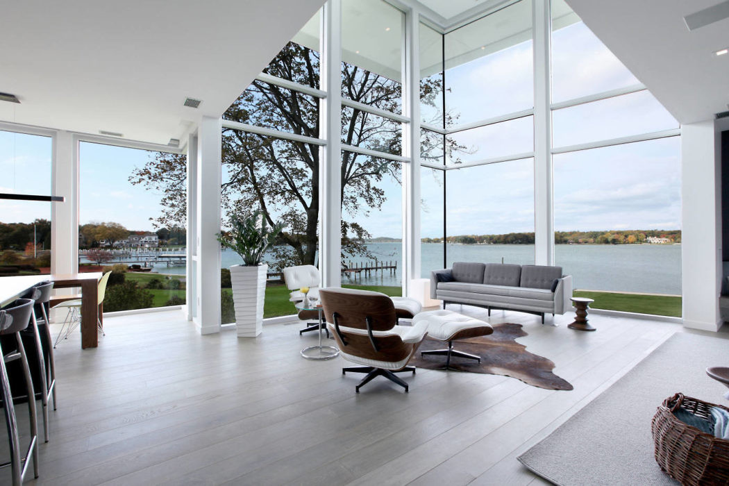 Modern living room with large windows overlooking a lake.