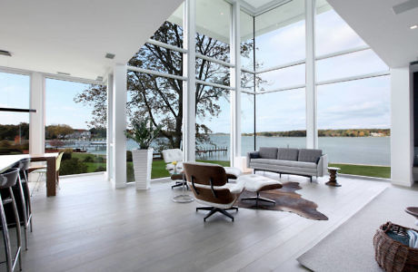 Modern living room with large windows overlooking a lake.