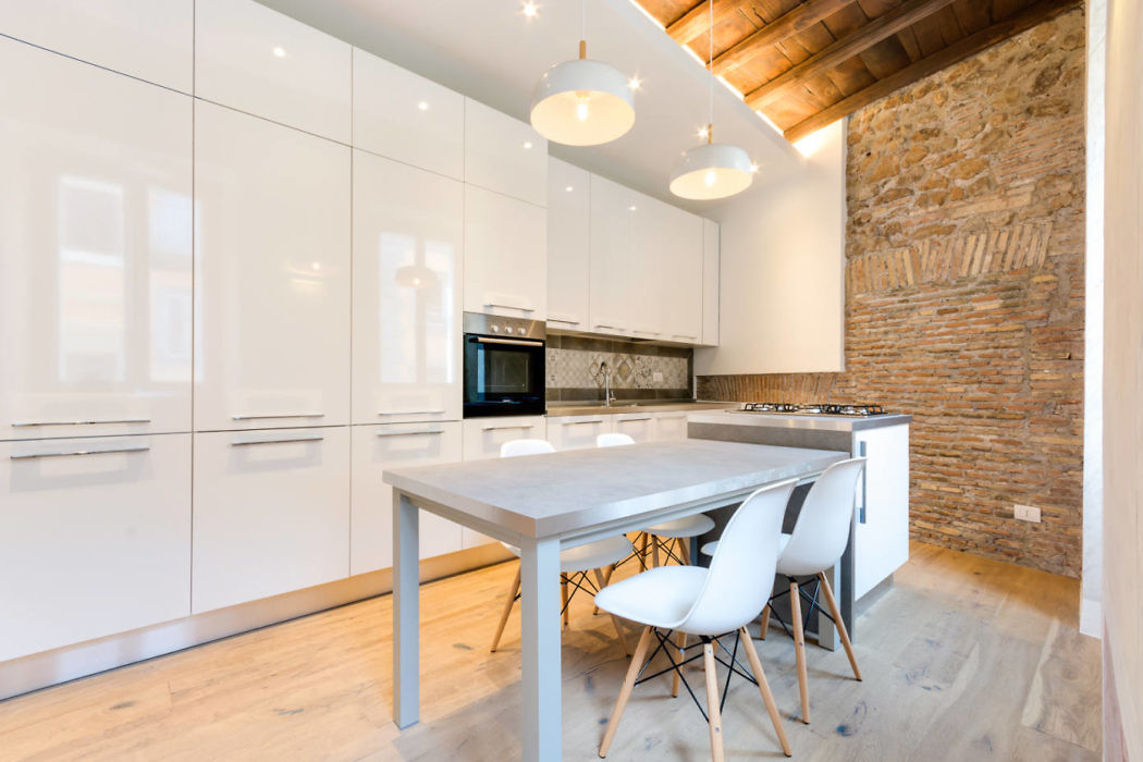 Modern kitchen with white cabinets, exposed brick wall, and central island.