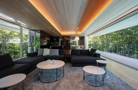 Modern living room with large windows, wooden ceiling, and black sectional sofa.