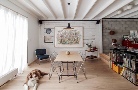 A rustic dining area with a floral wall art, wooden ceiling beams, and a canine companion.