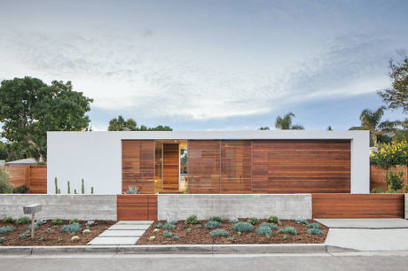 Modern single-story home with clean white walls, warm wood accents, and lush landscaping.