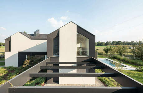 Modern two-story house with clean lines, large windows, and a pool surrounded by a well-designed garden.