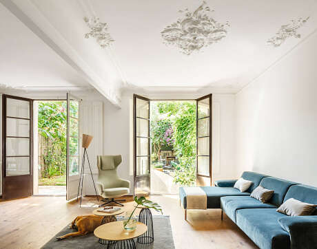 Elegant living room with large windows, ornate ceiling fixtures, and modern furnishings.