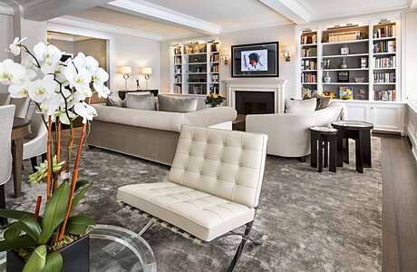 Elegant living room with built-in bookshelves, fireplace, and plush, tufted seating.