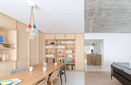 Minimalist interior with wooden furniture, built-in shelving, and colorful light fixtures.