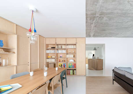 Minimalist interior with wooden furniture, built-in shelving, and colorful light fixtures.