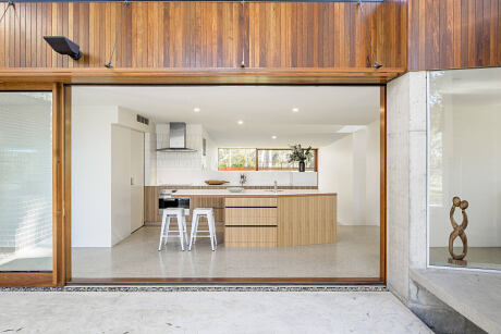 Minimalist kitchen interior with wooden accents, white countertops, and open layout.