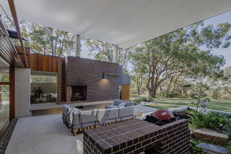 Modernist home design with brick fireplace, covered patio, and expansive green yard.