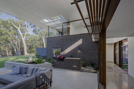 Minimalist outdoor living area with brick-patterned wall, wooden beams, and skylights.