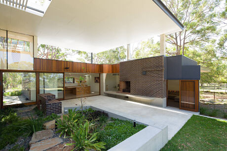 A modern residential design featuring a brick fireplace, wood accents, and a lush outdoor space.