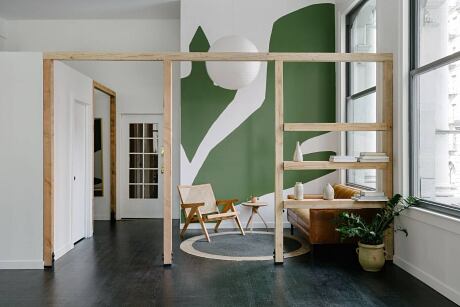 Minimalist living room with wood frame partition, green accent wall, and circular decor.