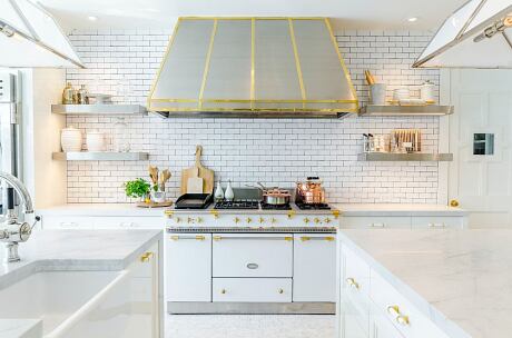 Modern white kitchen with gold accents and subway tiles.