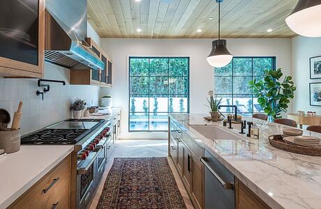 Chic kitchen with marble countertops, stainless appliances, and wooded view.