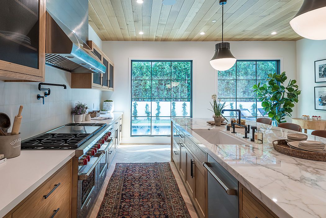 Chic kitchen with marble countertops, stainless appliances, and wooded view.