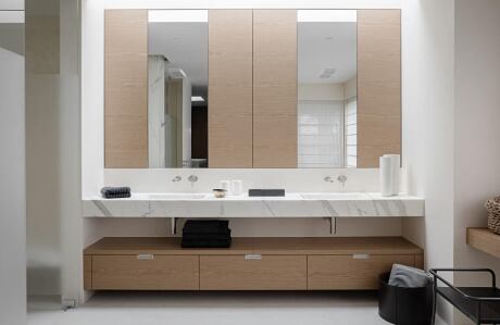 Minimalist vanity area with large mirror and beige cabinets.